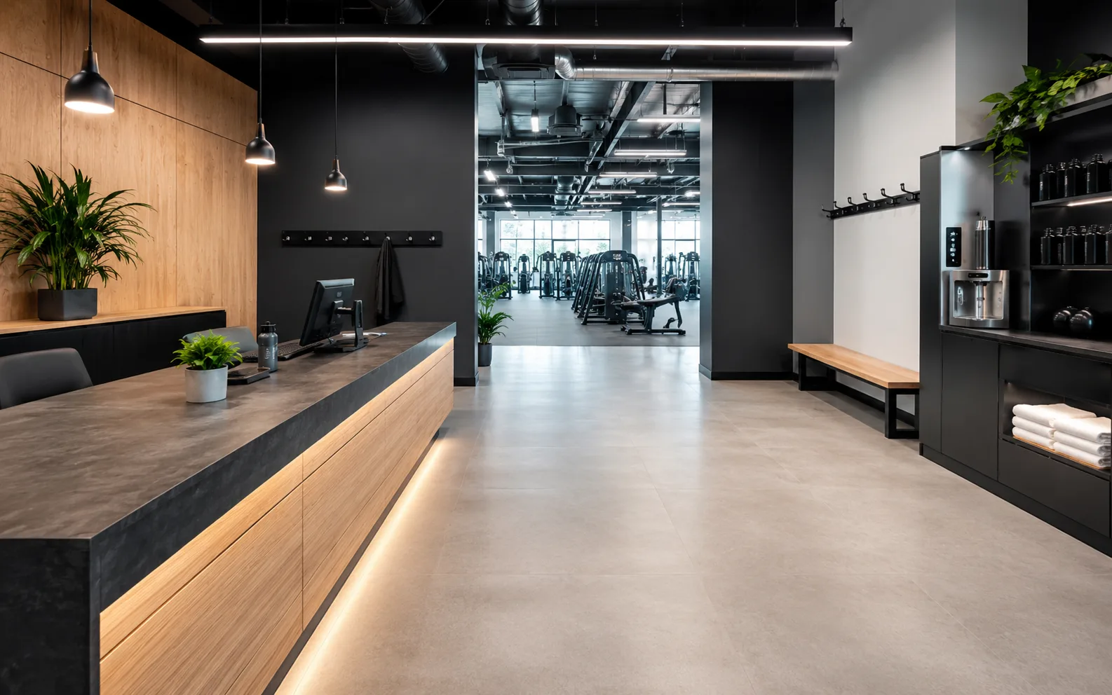 Studio reception desk with a wood accent wall, plants, and an open view through to the gym floor