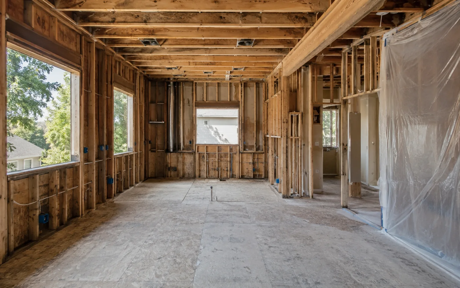 A room stripped to the studs mid-renovation, framing and subfloor exposed, before finish work begins